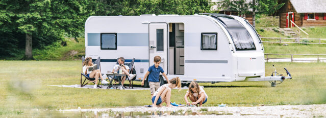 Familie på campingferie. Barna leker i sanden