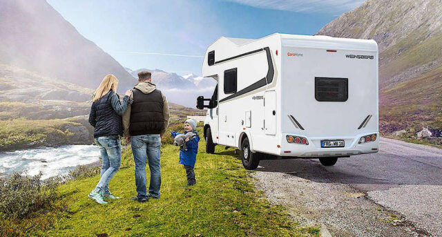 En familie som står ved siden av en bobil