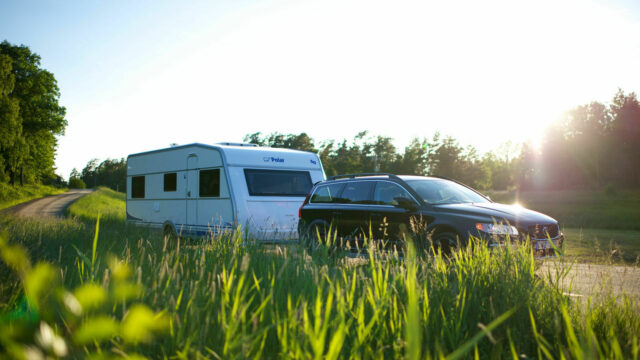Bil som drar campingvogn på en solfylt vei