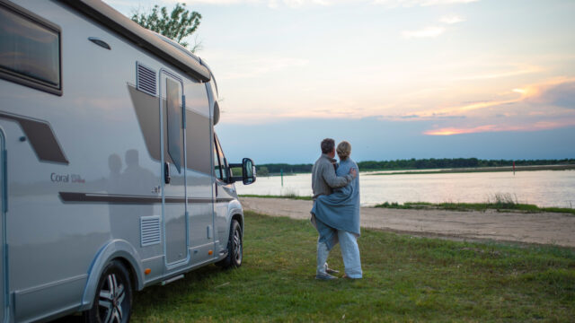 To personer som står ved bobilen sin og nyter solnedgangen